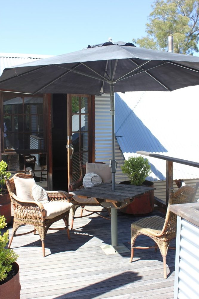 Sunny deck with wicker chairs under a large umbrella
