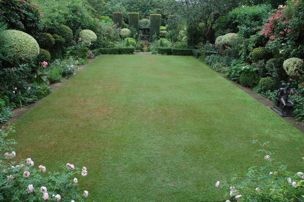 Long green lawn framed by clipped hedges and flowering borders